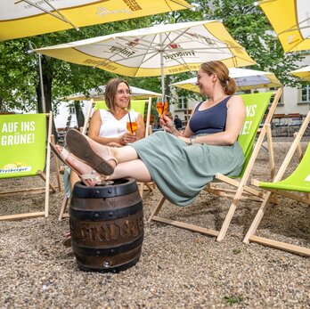 Zwei Frauen im Liegestuhl trinken einen Aperol